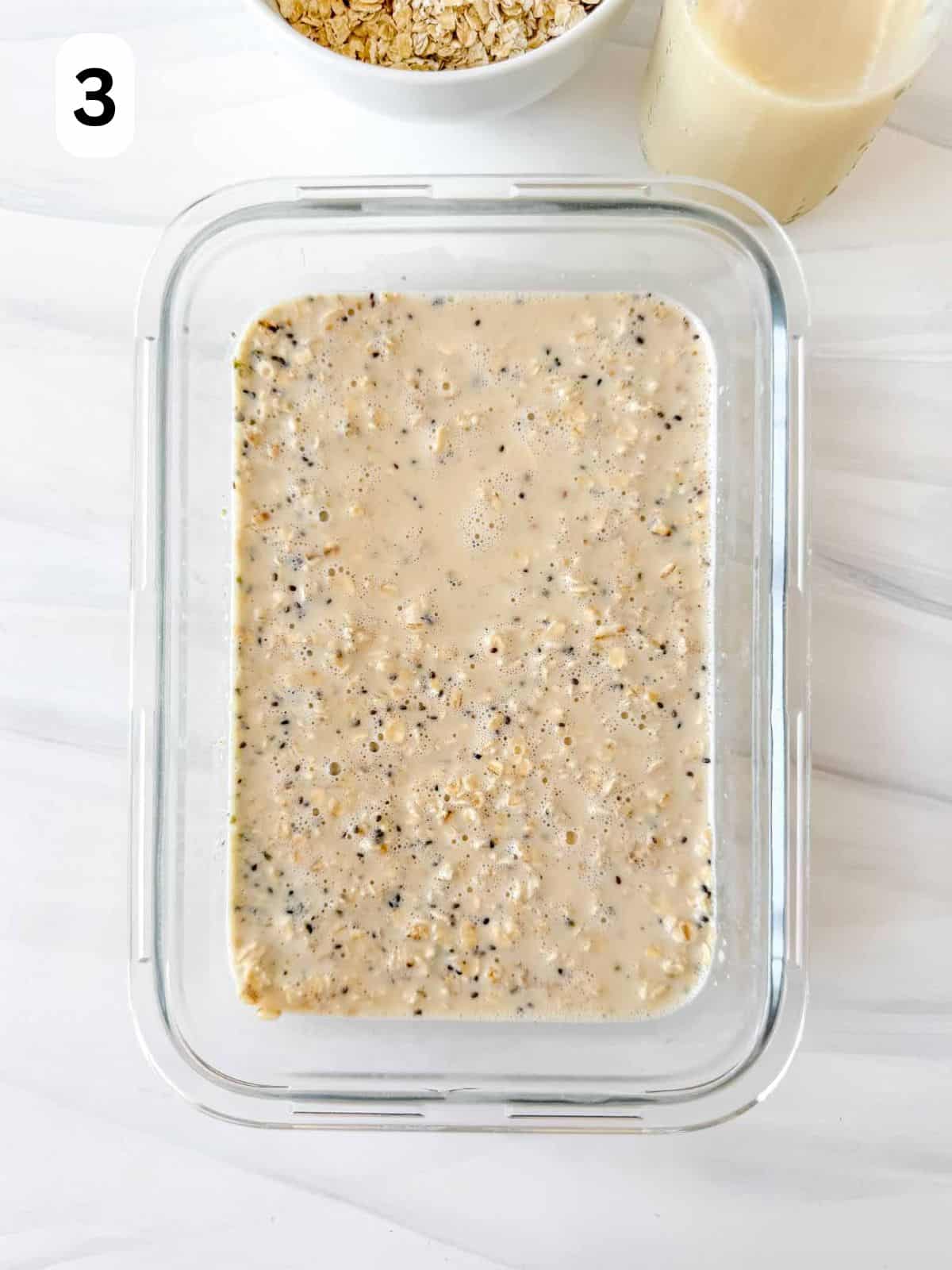 overnight oats with hemp seeds soaking in milk in a glass dish labelled number three.