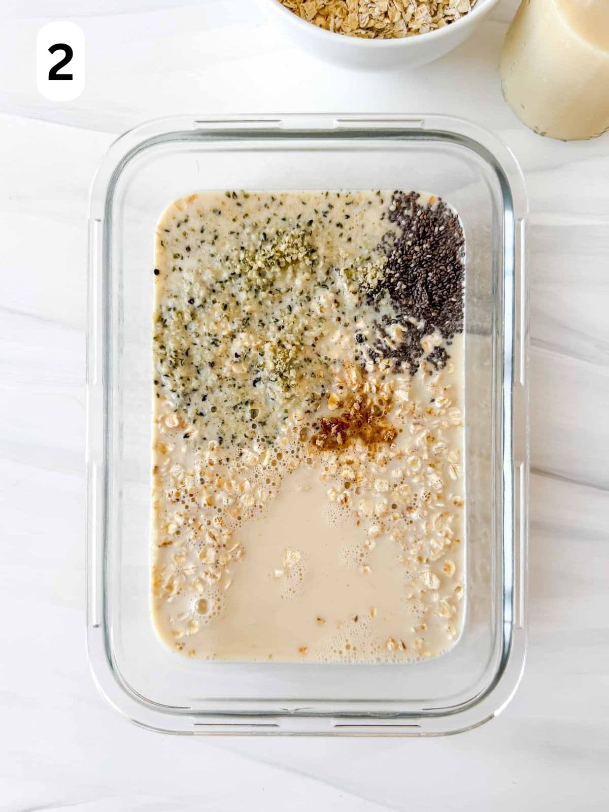 oats, hemp seeds, chia seeds and ground ginger in plant milk in a glass dish labelled number two.