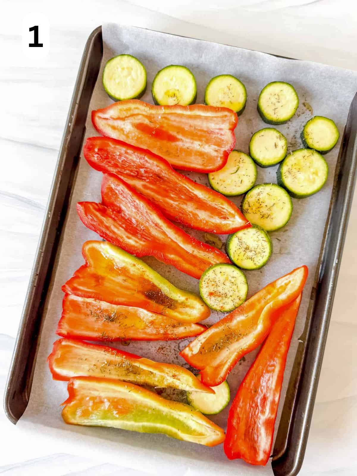 sweet pointed red peppers and zucchini rounds on a lined baking sheet labelled number one.