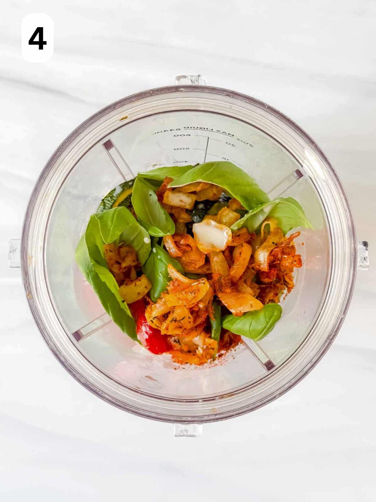 roasted red peppers, zucchini, basil leaves and onion mix in a blender cup labelled number four.
