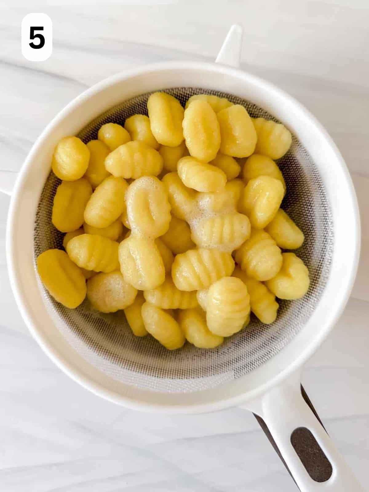 cooked gnocchi in a sieve labelled number five.