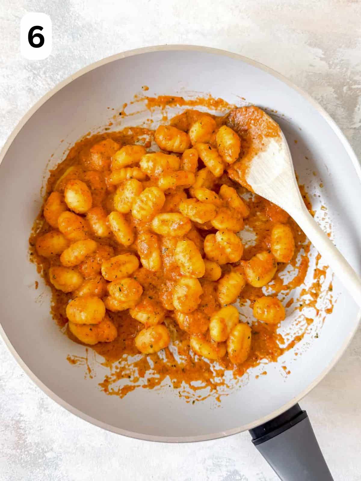 gnocchi in red pepper sauce in a skillet pan labelled number six.