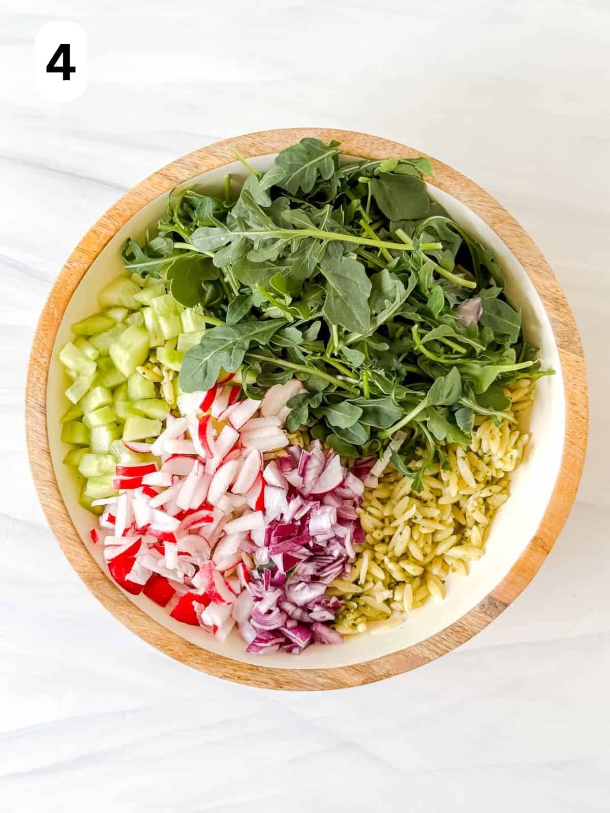 cooked orzo pasta, arugula, diced cucumber, radish and red onion in a salad bowl labelled number four.
