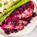 blackberry chicken on a white plate with asparagus and mashed potatoes.