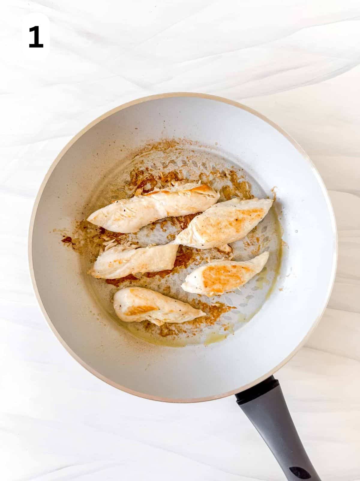 browned chicken breasts in a skillet labelled number one.
